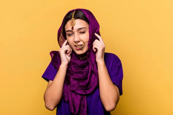 若いですインドの女性は手で耳をカバー黄色の背景に隔離された伝統的なサリーの服を着て — ストック写真