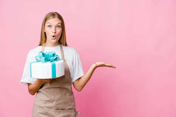 Young Russian Baker Woman Holding Delicious Cake Impressed Holding Copy — Stock Photo, Image