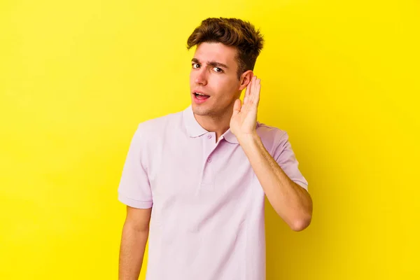Joven Hombre Caucásico Aislado Sobre Fondo Amarillo Tratando Escuchar Chisme —  Fotos de Stock