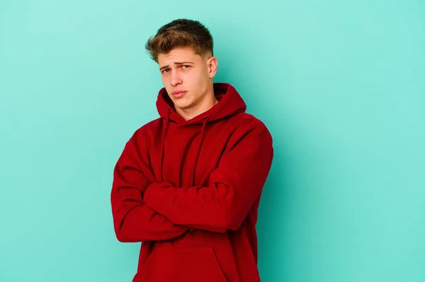 Joven Hombre Caucásico Aislado Sobre Fondo Azul Sospechoso Incierto Examinándote —  Fotos de Stock