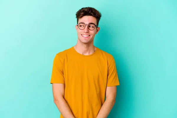 Jovem Caucasiano Isolado Fundo Azul Olha Para Lado Sorridente Alegre — Fotografia de Stock