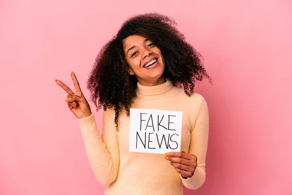 年轻的非洲裔美国卷曲女子 拿着假新闻站在一个欢快无忧无虑的标语牌上 用手指展示着一个和平的象征 — 图库照片