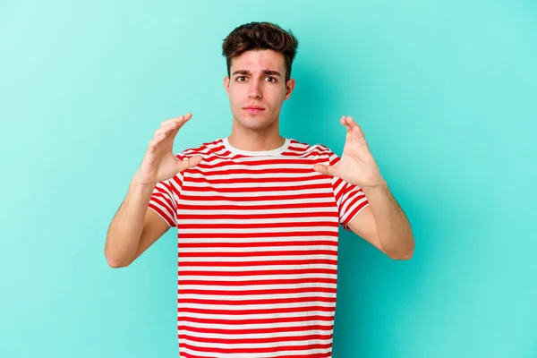 Young Caucasian Man Isolated Blue Background Holding Something Palms Offering — Stock Photo, Image