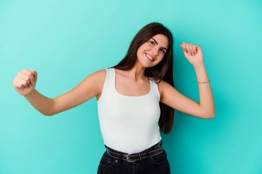 Genç beyaz kadın mavi arka planda izole edilmiş dans ediyor ve eğleniyor..