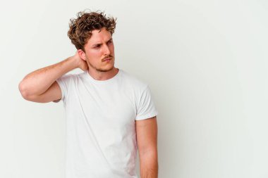 Beyaz arka planda izole edilmiş genç beyaz bir adam kafasının arkasına dokunuyor, düşünüyor ve bir seçim yapıyor..