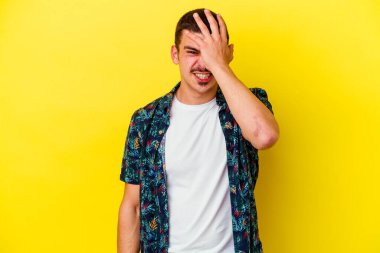 Sarı arka planda izole edilmiş genç beyaz adam bir şeyi unutuyor. Alnına avuç içi ve kapalı gözlerle vuruyor..