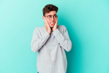 Kafkasyalı genç adam mavi arka planda izole edilmiş korkmuş ve korkmuş..