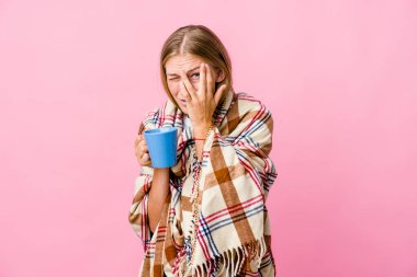 Genç Rus kadın battaniyeye sarılmış kahvesini yudumluyor parmaklarıyla gözünü kırpıyor korkmuş ve gergin..