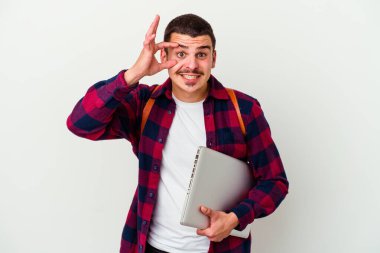 Beyaz arka planda izole edilmiş bir dizüstü bilgisayar tutan beyaz tenli genç bir öğrenci başarı fırsatı bulmak için gözlerini açık tutuyor..