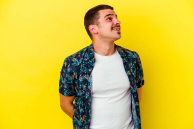 Sarı arka planda izole edilmiş, rahat ve mutlu bir şekilde gülen, boynunu uzatmış, dişlerini gösteren beyaz bir adam..