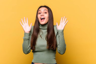 Sarı arka planda izole edilmiş genç Hintli kadın gökyüzüne haykırıyor, yukarı bakıyor, hayal kırıklığına uğramış..