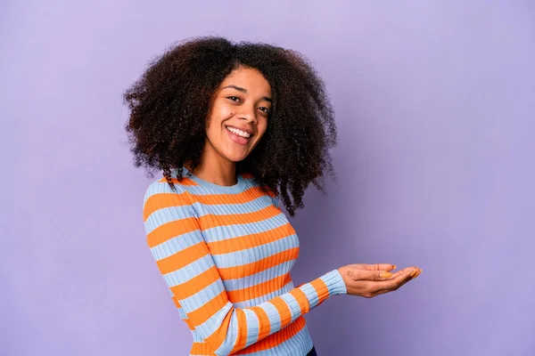 Joven Mujer Rizada Afroamericana Aislada Sobre Fondo Púrpura Sosteniendo Espacio —  Fotos de Stock