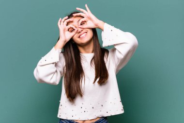 Mavi arka planda izole edilmiş genç Hintli kadın gözlerinde sorun olmadığını gösteriyor.