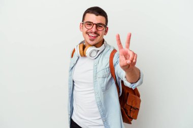 Beyaz arka planda izole edilmiş müzik dinleyen beyaz tenli genç bir öğrenci zafer işareti gösteriyor ve gülümsüyor..