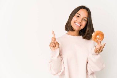 Genç İspanyol kadın donut yiyor. Bir numarayı parmaklarıyla gösteriyor..