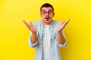 Sarı arka planda izole edilmiş genç beyaz adam şaşırdı ve şok oldu..