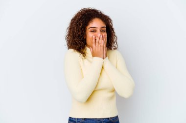 Beyaz arka planda izole edilmiş genç Afrikalı Amerikalı bir kadın bir şeylere gülüyor, elleri ağızlarını kapatıyor..