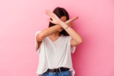 Pembe arka planda izole edilmiş genç beyaz kadın iki kolu çapraz tutuyor, inkar kavramı.