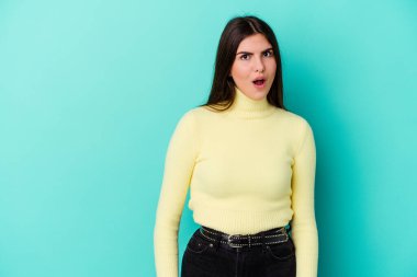 Mavi arka planda izole edilmiş beyaz bir kadın gördüğü bir şey yüzünden şoka uğruyor..