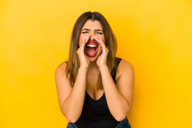 Sarı arka planda izole edilmiş genç bir Hintli kadın heyecanlı bir şekilde bağırıyor..