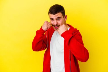 Sarı arka planda izole edilmiş genç beyaz adam bir tartışma yüzünden yumruk, öfke, kavga atıyor, boks yapıyor..
