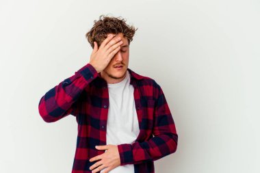 Beyaz arka planda izole olmuş genç beyaz bir adam başı ağrıyor, yüzüne dokunuyor..