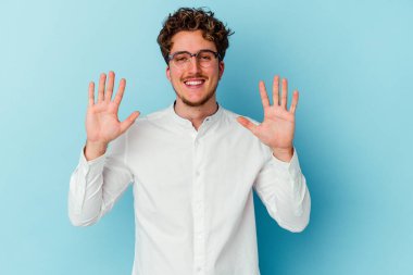 Kafkasyalı genç iş adamı mavi arka planda izole edilmiş. Elleriyle on numarayı gösteriyor..