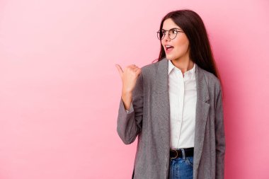 Kafkasyalı genç bir iş kadını pembe arka plan noktalarına izole edilmiş başparmak uzakta, gülüyor ve kaygısız.