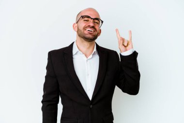 Genç, beyaz, kel bir adam mavi arka planda izole edilmiş. Bir devrim hareketi olarak boynuzları gösteriyor..