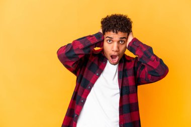 Genç Afro-Amerikalı kıvırcık adam, mor kulaklarla izole edilmiş, yüksek sesli sesler duymamaya çalışıyor..