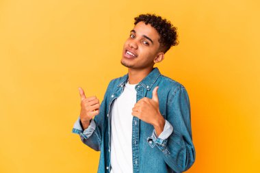 Genç Afro-Amerikalı kıvırcık adam mor üzerine izole edilmiş, iki parmağını da kaldırıyor, gülümsüyor ve kendinden emin..