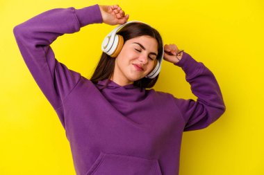 Kulaklıklı müzik dinleyen beyaz bir kadın pembe arka planda izole edilmiş kollarını uzatan, rahat bir konumda..