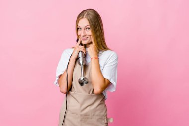 Genç Rus aşçı elinde bir elektrikli mikser tutuyor. İki seçenek arasında kuşkuları var..