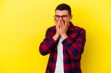 Sarı arka planda izole edilmiş genç, beyaz bir adam bir şeye gülüyor, ağızlarını elleriyle kapatıyor..