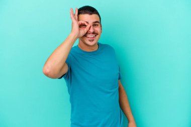 Kafkasyalı genç adam mavi arka planda izole edildi. Heyecanlı görünüyor..