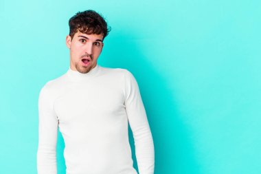 Kafkasyalı genç adam mavi arka planda izole edilmişti. Gördüğü bir şey yüzünden şok olmuştu..