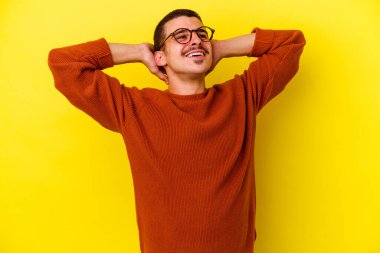 Sarı arka planda izole edilmiş, elleri başının arkasında kendinden emin genç, beyaz bir adam..