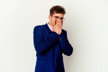 Beyaz arka planda izole olmuş genç beyaz bir adam bir şeye gülüyor, elleri ağızda..