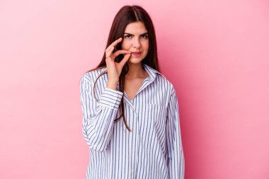 Pembe arka planda izole edilmiş genç beyaz kadın parmakları dudaklarında bir sır saklıyor..