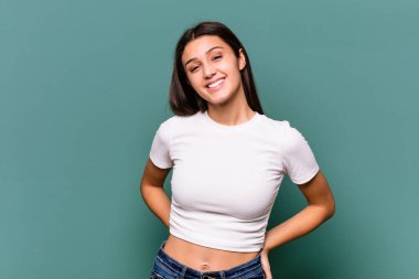 Mavi arka planda izole edilmiş genç Hintli kadın mutlu, güler yüzlü ve neşeli.