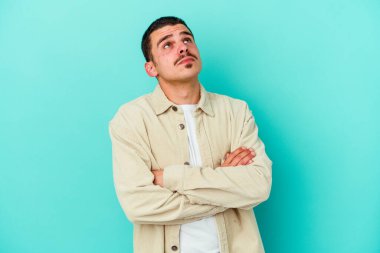 Mavi arka planda izole edilmiş genç beyaz adam tekrarlanan bir görevden yoruldu..