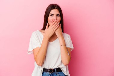 Pembe arka planda izole edilmiş beyaz bir kadın elleriyle ağzını kapatırken şok oldu..