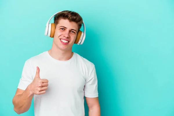 Ung Kaukasier Man Lyssnar Musik Med Hörlurar Isolerade Blå Bakgrund — Stockfoto