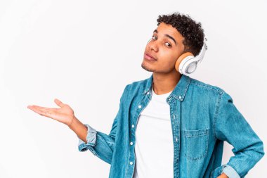 Genç Afro-Amerikan kıvırcık adamı, izole edilmiş, kulaklıklı müzik dinliyor, avuç içinde fotokopi alanı ve belinde başka bir el tutuyor..