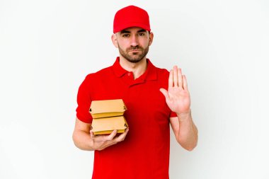 Beyaz arka planda izole edilmiş beyaz tenli genç teslimatçı elini uzatmış, dur işareti göstererek seni engelliyor..
