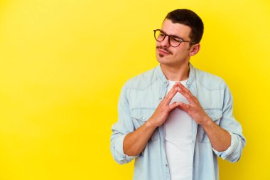 Kafkasyalı genç havalı adam sarı arka planda izole edilmiş bir plan yapıyor, bir fikir kuruyor..