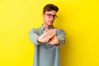 Sarı arka planda izole edilmiş genç beyaz adam elini uzatmış, dur işareti göstererek seni engelliyor..