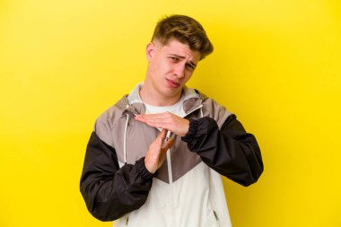 Sarı arka planda izole edilmiş genç beyaz adam bir mola hareketi gösteriyor..