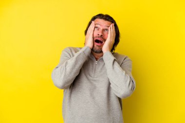 Orta yaşlı, beyaz bir adam sarı arka planda izole edilmiş sızlanıyor ve ağlıyordu..
