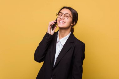 Genç Hintli iş kadını sarı arka planda izole bir şekilde telefonla konuşuyor.